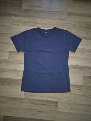 Mörkblå basic t-shirt från 157 - En enkel mörkblå t-shirt från 157 med rund hals och korta ärmar. Tillverkad i mjuk bomull för en skön och avslappnad känsla. Perfekt att matcha med jeans eller shorts för en clean look.