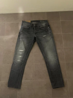 Dondup George W30 - Säljer ett par grå jeans från dondup med slitningar på framsidan. Jeansen är skinny fit och har en smal passform och är tillverkade i denim med lätt stretch. Perfekta för en avslappnad och trendig look. Hör av dig vid minsta lilla fundering, eller prisförslag.