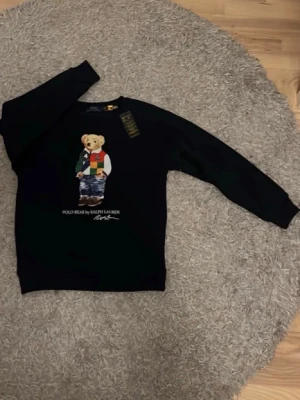 Svart sweatshirt Polo Bear Ralph Lauren - Svart sweatshirt från Ralph Lauren med ikoniska Polo Bear-trycket. Storlek på xs