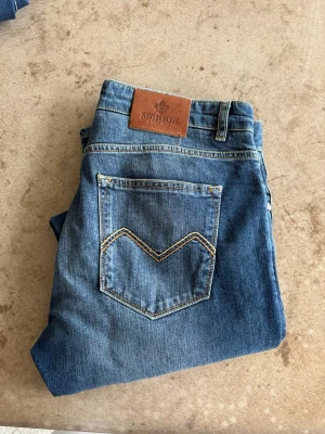 Blå jeans från Morris - Snygga blå jeans från Morris med klassisk femficksdesign och kontrastsömmar på bakfickan. Jeansen är i storlek 33/34 men sitter som en 31/32!