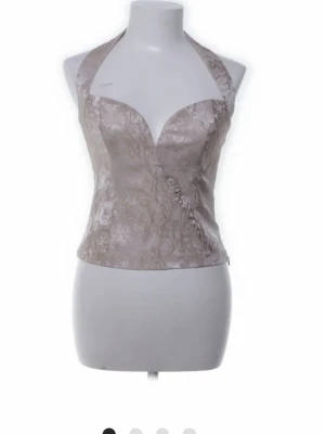 Champagnefärgad korsettopp  - Snygg champagnefärgad korsettopp med halterneck och djup v-ringning. Från reformation och nypris är ca 2000 kr, finns ej att köpa längre i denna färg. Använd 1 gång, finns inga defekter!❤️