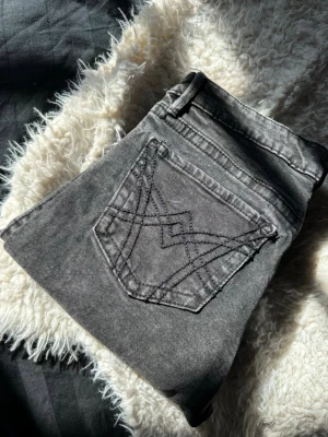 Svarta jeans med broderade bakfickor - Säljer ett par svarta jeans med snygga broderade detaljer på bakfickorna. Perfekta för dig som gillar en trendig look. Det är bootcut Low Waist jeans. Knappt använda. 
