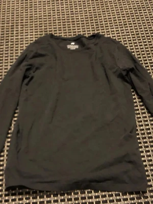 Svart långärmad topp H&M - En basic svart långärmad topp från H&M. Tillverkad i mjuk bomull med rund halsringning och enkel, stilren design. Perfekt att matcha med jeans eller kjol för en clean look.