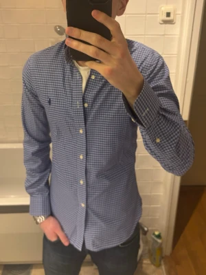 Blårutig skjorta från Ralph Lauren - Säljer en blårutig skjorta från Ralph Lauren i slim fit-modell. Skjortan har klassisk krage, knappar framtill och lång ärm. Hör gärna av vid fler funderingar! :)