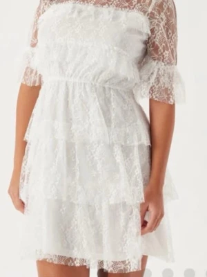 Vit spetsklänning med volanger - Superfin vit kortklänning i spets med volangdetaljer och halvtransparenta ärmar.💕 Klänningen har aldrig använts och är då i ett mycket fint skick😇Klänningen har hög hals, markerad midja och flera lager volanger som ger en romantisk look. Perfekt för sommarens alla tillfällen!💕