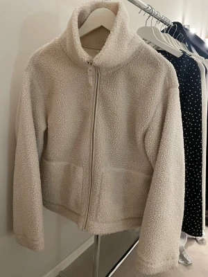 Beige teddyjacka HM - Mysig beige teddyjacka med hög krage och dragkedja framtill. Jackan har två fickor.