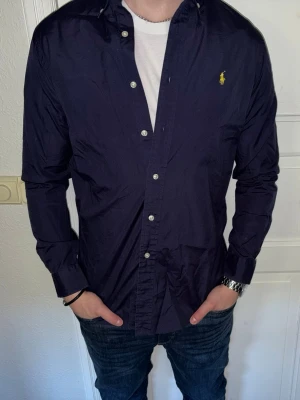 Mörkblå skjorta från Ralph Lauren - Mörkblå skjorta från Ralph Lauren i storlek S.  Fint skick till ett bra pris. Nypris: 1995kr. Mitt pris: 349kr. Vid frågor eller funderingar, tveka inte att höra av dig.