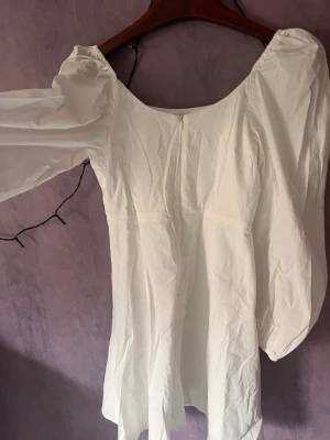 Vit studentklänning  - Vit klänning från Nelly, helt slutsåld! Superfin modell med puffärmar, fyrkantig urringning och markerad midja. Sitter jättefint och passar perfekt till sommar, fest eller student.
