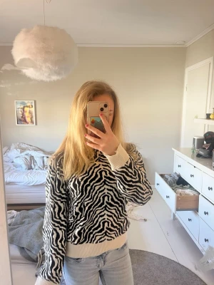 Zebramönstrad stickad tröja - Säljer en ascool stickad tröja med svartvitt zebramönster och ribbade muddar vid ärmslut och längst ned på tröjan. Perfekt nu till våren då den inte är super varm heller💕