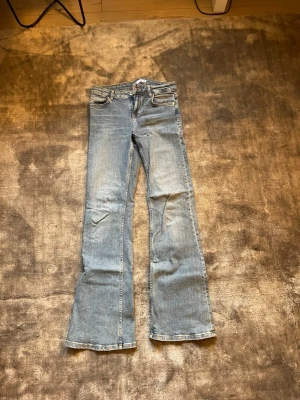 Bootcut jeans från Zara ljusblå - Säljer ett par ljusblå bootcut jeans från Zara med klassisk femficksmodell och dragkedjegylf. Jeansen har en lätt utsvängd passform nedtill och är tillverkade i denim med synliga sömmar. Perfekta för en avslappnad och trendig look. Lågmidjade, stretchiga så passar 36 också