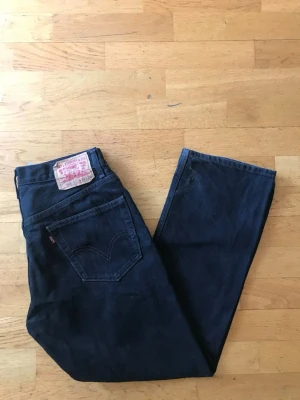 Levi's 505 mörkblå jeans W32 L29 - Klassiska Levi's 505 jeans i mörkblå denim med raka ben och femficksmodell. Tidlös design med ikonisk läderpatch bak och röd Levi's-tagg på bakfickan. Perfekta för dig som gillar en clean och avslappnad look.