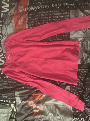 Rosa långärmad tröja från Polarn O. Pyret - En enkel och snygg rosa långärmad tröja från Polarn O. Pyret. Tröjan har rund halsringning och är gjord i mjukt bomullsmaterial. Perfekt för en avslappnad och bekväm stil.