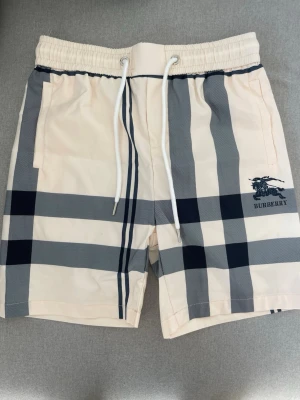 Burberry shorts - Vit/beiga burberry badbyxor perfekt för sommaren. Strolek M lite små i passform passar runt s-m. Aldrig använda skriv vid frågor.