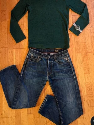 Blå raka jeans från Replay Jeans - Säljer ett par klassiska blå jeans från replayJeans med raka ben och snygga slitningar. Jeansen har fem fickor, kontrastsömmar och en patch bak i midjan. Tillverkade i slitstark denim som ger en cool och avslappnad look.