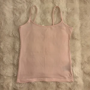 Ljusrosa linnetopp med smala band - Säljer en enkel och stilren ljusrosa linnetopp med smala axelband. Toppen är ärmlös och har en rak passform, perfekt att matcha med jeans eller kjol. Materialet känns mjukt och lätt mot huden.