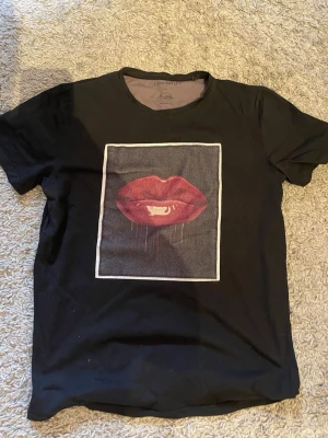 Svart t-shirt Limitato Sugar Pop Pink - Cool svart t-shirt från Limitato med ett stort tryck av röda läppar. Använd men inte någon anmärkningsvärt fel vad jag ser.