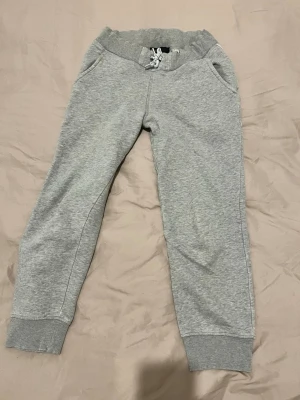 Grå mjukisbyxor Peak Performance - Säljer ett par grå mjukisbyxor från Peak Performance med ribbade muddar, dragsko i midjan och två sidofickor och bakficka. Tillverkade i mjukt bomullsmaterial, perfekta för chill dagar. Snygg och enkel design. 