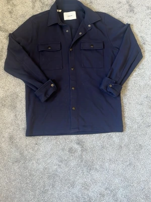 Mörkblå overshirt från Selected - Tja säljer nu den här snygga overshirten från selected! Perfekt nu till våren eller sena sommarkvällar! Storlek S, Nypris 799kr, skick 9/10! Hör av er vid minsta lilla fråga eller fundering! 