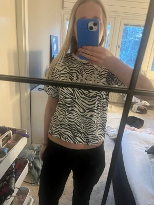 Zebramönstrad t-shirt från Puma - Säljer en svartvit zebramönstrad t-shirt från juicy couture med logga tryckt framtill. T-shirten har rund halsringning och korta ärmar. Materialet är mjukt och skönt, perfekt för en avslappnad och trendig look.