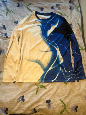 Mjukisbyxor med blått abstrakt mönster - Säljer ett par mjukisbyxor med unikt abstrakt mönster i blått, svart och beige. Byxorna har resår i midjan med dragsko och muddar vid bensluten. Materialet känns mjukt och stretchigt, perfekt för chill dagar. Snygg och modern design som sticker ut.