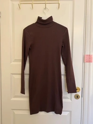 Brun ribbad poloklänning Bik Bok - Säljer en brun ribbad poloklänning från Bik Bok. Klänningen är kort, har lång ärm och en hög polokrage. Materialet är stretchigt och sitter tight på kroppen, perfekt för en trendig och enkel look.