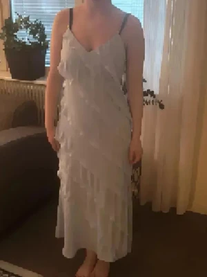 Ljusblå långklänning med volanger - Säljer en elegant ljusblå långklänning med tunna axelband och v-ringning. Klänningen har flera lager av volanger som ger ett romantiskt och luftigt intryck. Perfekt för dig som vill ha en feminin och stilren look. Köpt sacond hand och utan lappar. Passar xs/s