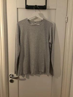 grå basic långärmad tröja - En enkel och stilren ljusgrå långärmad tröja med rund hals. Tröjan är tillverkad i ett mjukt och tunt material, perfekt för lager på lager eller som den är. Passar till det mesta och har en avslappnad passform.