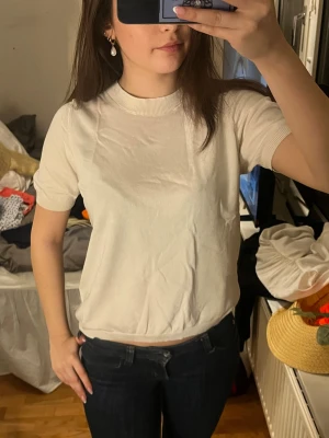 Vit basic t-shirt med kort ärm - En enkel och stilren vit t-shirt med korta ärmar och rund hals. T-shirten har en normal passform och är tillverkad i mjuk bomull, perfekt för en clean och avslappnad look.