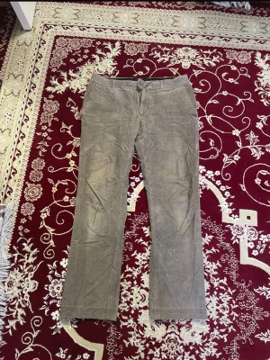 Khaki/Taupe Dressmann Manchesterbyxor - Säljer ett par khaki/taupe manchesterbyxor med rak passform och klassisk femficksdesign. Byxorna har tydlig manchesterstruktur och stängs med knapp och dragkedja. Perfekta för dig som gillar retrostil. 2 för 120 kr på alla herrbyxor. 