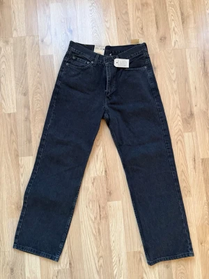 Svarta raka jeans från Levi's - Säljer ett par svarta raka jeans från Levi's med klassisk femficksdesign och hög midja. Jeansen har en enkel look utan slitningar och är tillverkade i kraftig denim. Perfekta till en avslappnad stil och passar till det mesta. De är helt nya aldrig använda säljer de, då de var lite för små för mig och glömde bort att returnera så öppetköpet gick ut!