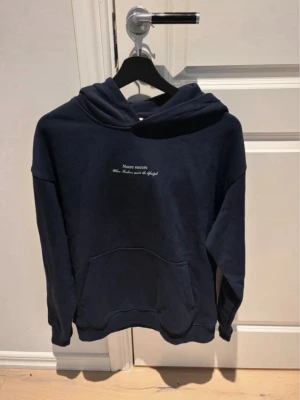 Mörkblå hoodie notre succés - Snygg mörkblå hoodie med huva och känguruficka. På bröstet står det 'Notre succès' och på ryggen finns ett stort tryck med texten 'Dolce Vita Lago di Como' samt ett svartvitt motiv av Comosjön. Perfekt för dig som gillar stilrena men ändå unika plagg.