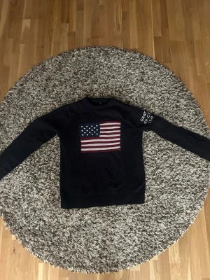 Marinblå  Gant tröja med USA-flagga - Snygg svart tröja från Gant med amerikanska flaggan , en väldigt fin tröja , inga defekter och perfekt in för sommaren ! 