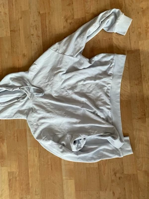 Ljusgrå hoodie från 157 - En enkel och clean ljusgrå hoodie från 157 med huva och dragsnören. Tillverkad i mjukt bomullsmaterial och har ribbade muddar vid ärmslut och nederkant. Perfekt för en avslappnad och chill stil.