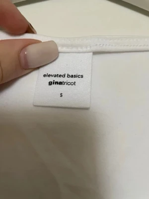 Vit linnetopp från Gina Tricot - Säljer en enkel och stilren vit linnetopp från Gina Tricot, kollektionen Elevated Basics. Toppen har breda axelband och en rak, något djupare urringning fram. Perfekt att matcha med jeans eller kjol för en clean look.