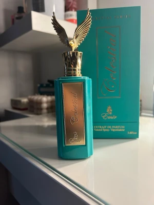 Celestial parfym från Emir - Celestial parfym från Emir i en lyxig turkos flaska med gulddetaljer och en unik kork formad som en gyllene örn med utbredda vingar. Flaskan har en elegant rektangulär form och levereras i matchande turkos förpackning med guldtext. Har inte använt den. 