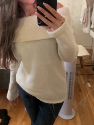 Off shoulder stickad tröja Gina Tricot - Krämvit stickad off shoulder-tröja från Gina Tricot. Tröjan har bred krage som vilar över axlarna och långa ärmar. Mjuk och skön kvalitet, perfekt för mysiga dagar. Enkel att styla med jeans eller kjol.