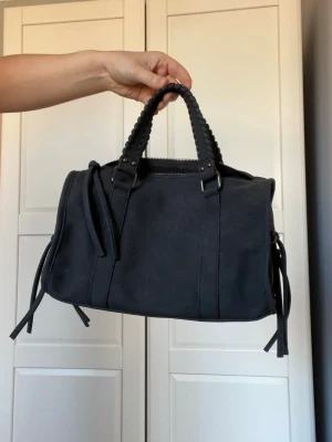 Svart handväska med fransar  - Säljer denna så snygga handväskan som är köpt på en marknad utomlands. Längd 19 cm höjd 15 cm och bredd 13 cm. Väldigt bra skick den har inga defekter eller liknande💗💗Kolla även min profil där jag bland annat säljer flera jeans