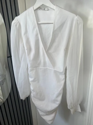 Studentklänning från Nelly, XS - Snygg studentklänning från NLY One med v-ringning och långa, lätt puffade ärmar. Endast använt den en gång på min studentmottagning. Pris kan diskuteras💖