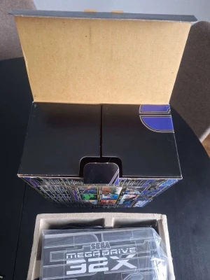 Sega Mega Drive 32X konsol - Säljer en Sega Mega Drive 32X konsol i svart plast med originalkartong, manual och strömadapter. Konsolen har en futuristisk design och är ett tillbehör till Mega Drive som ger möjlighet att spela 32-bitars spel. Perfekt för retrospelare och samlare.
