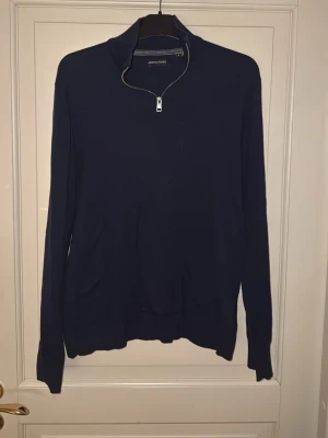 Mörkblå halvzip från Jack & Jones - Mörkblå tröja från Jack & Jones med halv dragkedja och hög krage. Tillverkad i mjukt stickat material och har långa ärmar samt ribbade muddar. Enkel och stilren design som passar till många olika looks.                                    Pris kan diskuteras! Hämtas i Torslanda eller så fraktar jag.