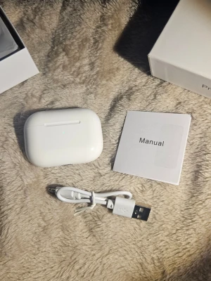 TWS trådlösa bluetooth in-ear hörlurar / earbuds - Snygga vita trådlösa in-ear hörlurar med laddningsetui. Kommer med USB-laddningskabel och manual. Hörlurarna har en stilren och kompakt design i plast och passar perfekt för musik, poddar och samtal på språng.