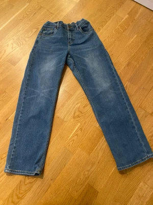 Blåa Levi's jeans - Klassiska blå jeans från Levi's med rak passform och fem fickor. Jeansen har normal midja, knappgylf och är tillverkade i slitstark denim. Perfekta för en avslappnad och tidlös stil.