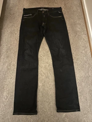 Mörk blåa  raka jeans från replay  - Säljer ett par mörk blåa  jeans från replay  med raka ben och klassisk femficksdesign. Jeansen har kontrastsömmar och är tillverkade i kraftigt denimtyg. Perfekta för dig som gillar en tidlös och enkel stil.