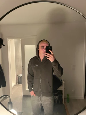Peak performance zip up - Säljer en mörkgrön hoodie med dragkedja och huva. Tryck i vitt på vänster bröst. Två stora fickor framtill och ribbade muddar vid ärmslut och nederkant. Perfekt för en chill och avslappnad stil.
