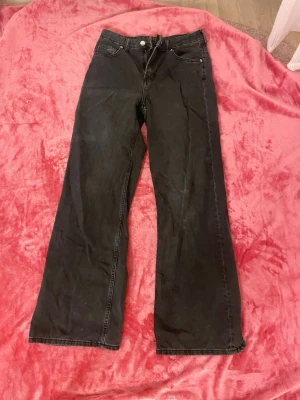 Svarta wide leg jeans från Divided - Säljer ett par svarta wide leg jeans från Divided by H&M. Jeansen har hög midja, klassisk femficksmodell och raka, vida ben. Perfekta för en avslappnad och trendig look. Materialet är denim i bomull.