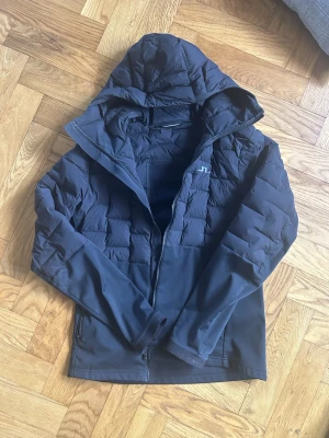 Svart pufferjacka från J.Lindeberg - Snygg svart pufferjacka från J. Lindenerg perfekt nu när våren är här. Samma jackor ligger uppe för över 1000 kronor här på plick. Finns små defekter i form av noppor (se bild 5) men som knappt syns. Nya säljs för ≈2000. Endast 499