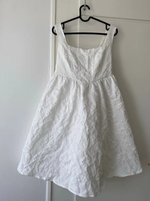 Vit spetsklänning med rosett - Superfin vit klänning med breda axelband som har blommigt spetsmönster och dragkedja som fungerar. Klänningen har en stor rosett i ryggen och ett tunt lager tylltyg (se sista bild) den går till lite över knäna på mig (170cm)  och är köpt på en vintagebutik i Italien men jag själv har aldrig använt den 🌟 väldigt bra skick för att vara vintage och vintagelukten är inte längre kvar 🔥