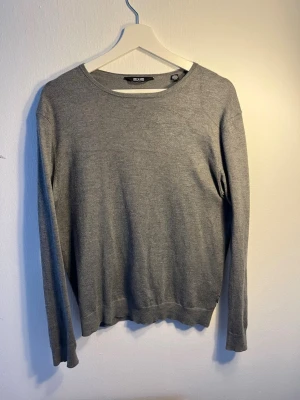 Grå stickad tröja från Only & Sons - En stilren grå stickad tröja från Only & Sons. Tröjan har rund halsringning, långa ärmar och är tillverkad i mjukt material som passar perfekt till lager på lager. Enkel design som funkar till det mesta.