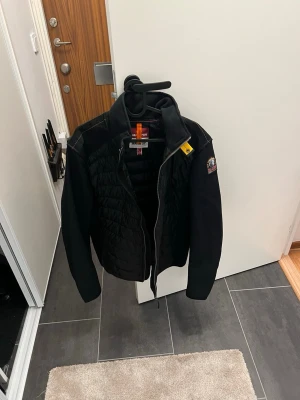 Svart jacka från Parajumpers - Säljer en svart jacka från Parajumpers med quiltad front, meshdetaljer och gul rem vid kragen. Jackan har dragkedja, patch på ärmen och orange detaljer vid nacken. Perfekt för dig som gillar sportig och modern stil. DEN ÄR HELT NY ALDRIG ANVÄND⚠️‼️ köpt för 4899
