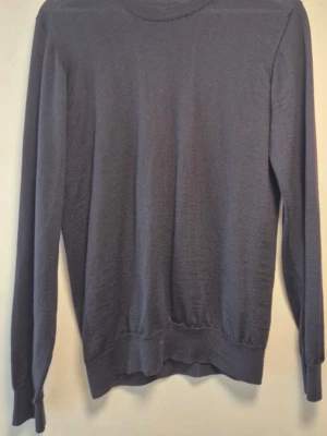 Mörkgrå stickad tröja Oscar Jacobson - Snygg mörkgrå stickad tröja från Oscar Jacobson med rund halsringning och ribbade muddar vid ärmslut och nederkant. Perfekt för lager på lager och enkel att matcha med olika stilar. Tillverkad i mjukt material för skön känsla.